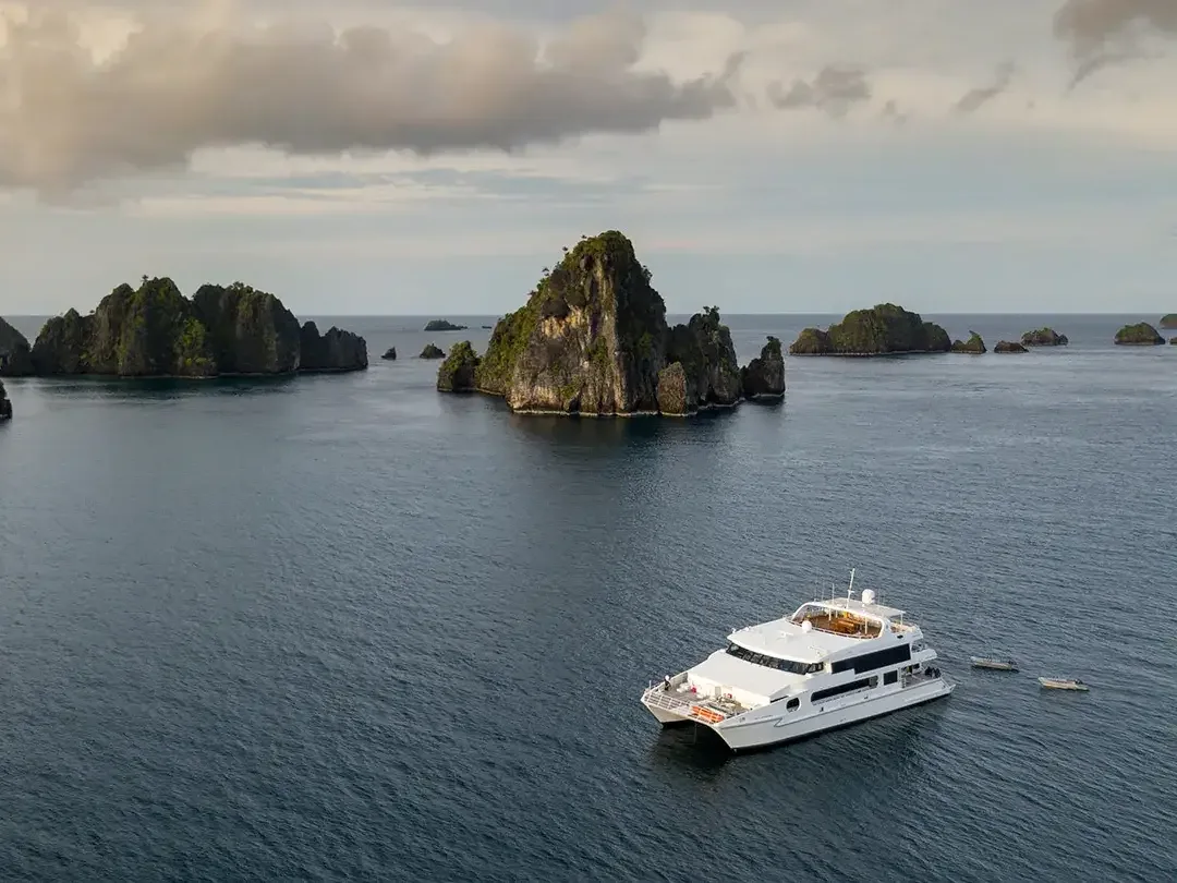 Power catamaran liveaboard anchored among karst islets in Raja Ampat